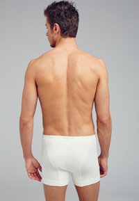 Białe bawełniane slipy z prążkowanym wykończeniem, z miękkim paskiem w talii z logo marki. Prosty design, dopasowany krój.