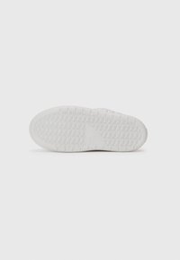 Suela de zapato de goma blanca con un patrón de agarre texturizado y detalle del logo. Forma plana y redondeada adecuada para calzado casual.
