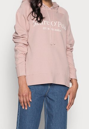 Felpa rosa realizzata in tessuto morbido, con cappuccio regolabile, logo frontale e polsini a coste, abbinata a jeans a gamba larga blu.