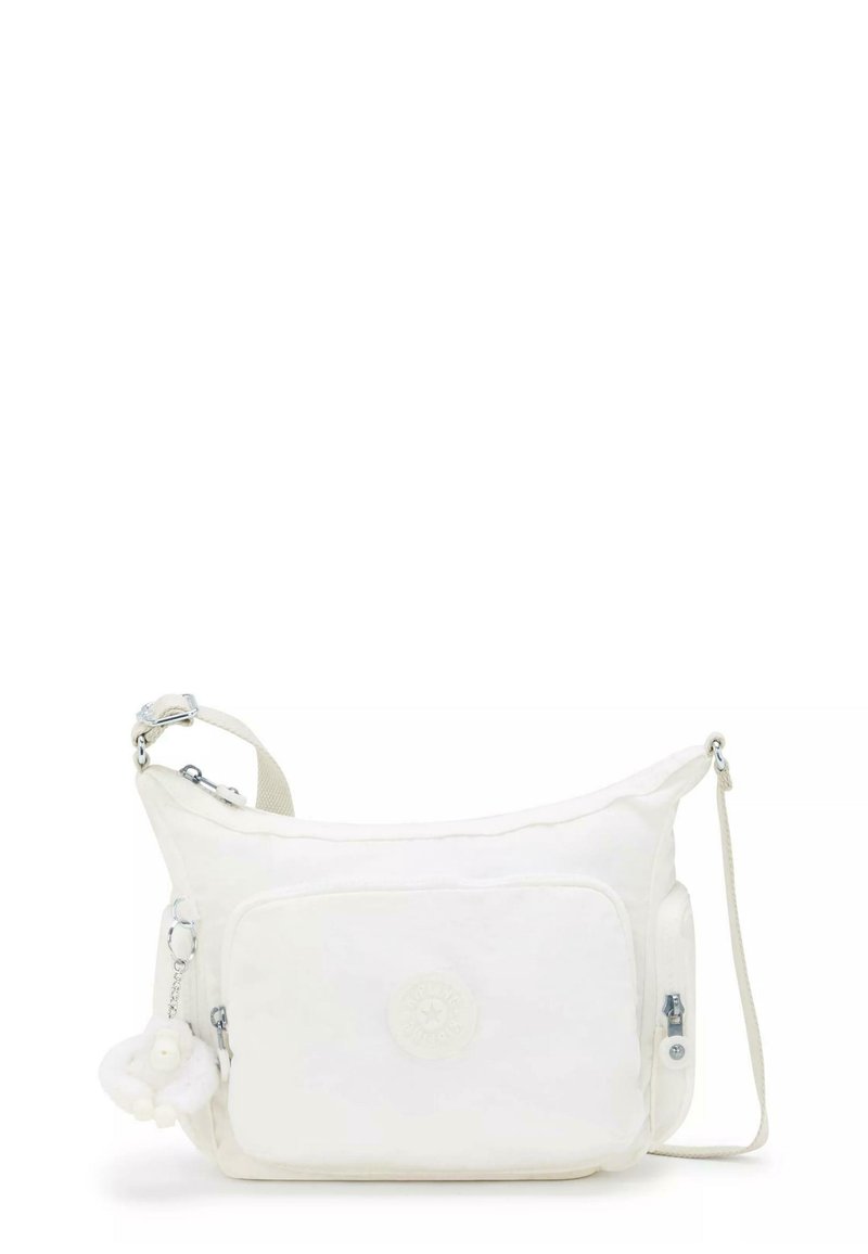 White crossbody bag featuring soft material, a main zip compartment, front pocket, and a removable charm. Adjustable strap and logo detail.