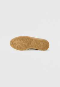 Schuhsohle aus Gummi mit einem strukturierten, honigwabengemuster für Traktion und Halt. Flache, abgerundete Form ohne sichtbare Markenkennzeichnung.