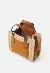 Piccola borsa a tracolla in suede marrone con rifiniture in shearling, doppie maniglie in pelle e chiusura a patta, con il marchio "JOOP!" sul fronte.