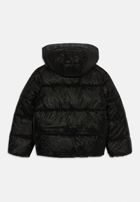 Veste puffer noire avec un design matelassé, capuche et finition texturée. Comprend un logo ton sur ton sur la capuche et un éclat brillant.