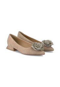 Ballerines en daim beige avec un bout pointu, un talon bas et épais, et un accent décoratif en perles en forme de rose sur chaque chaussure.
