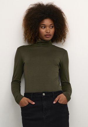 Maglione a collo alto verde oliva realizzato in materiale liscio, con maniche lunghe e una vestibilità attillata, abbinato a una gonna nera.