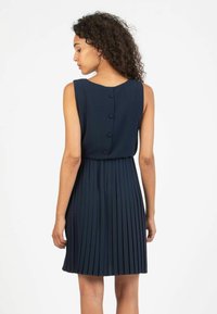 Abito senza maniche blu navy con gonna plissettata, texture liscia e particolare dettaglio dei bottoni lungo la parte posteriore.