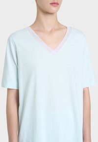 T-shirt azzurro a maniche corte con scollo a V, rifinita con bordino trasparente lungo il collo, che mette in risalto una texture morbida e liscia e una vestibilità rilassata.
