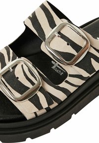 Sandales slides rayées zèbre noir et beige avec deux boucles argentées et une semelle noire texturée. Adaptées pour un usage décontracté.