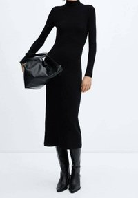 Robe noire à côtes avec des manches longues et un col haut, accompagnée d'un sac à main noir texturé et de bottes noires jusqu'aux genoux.