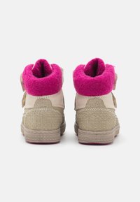 Beżowe buty typu high-top z różowym filcowym kołnierzem, teksturowanymi bokami i płaską podeszwą. Dwa paski na rzepy dla pewnego zapięcia.