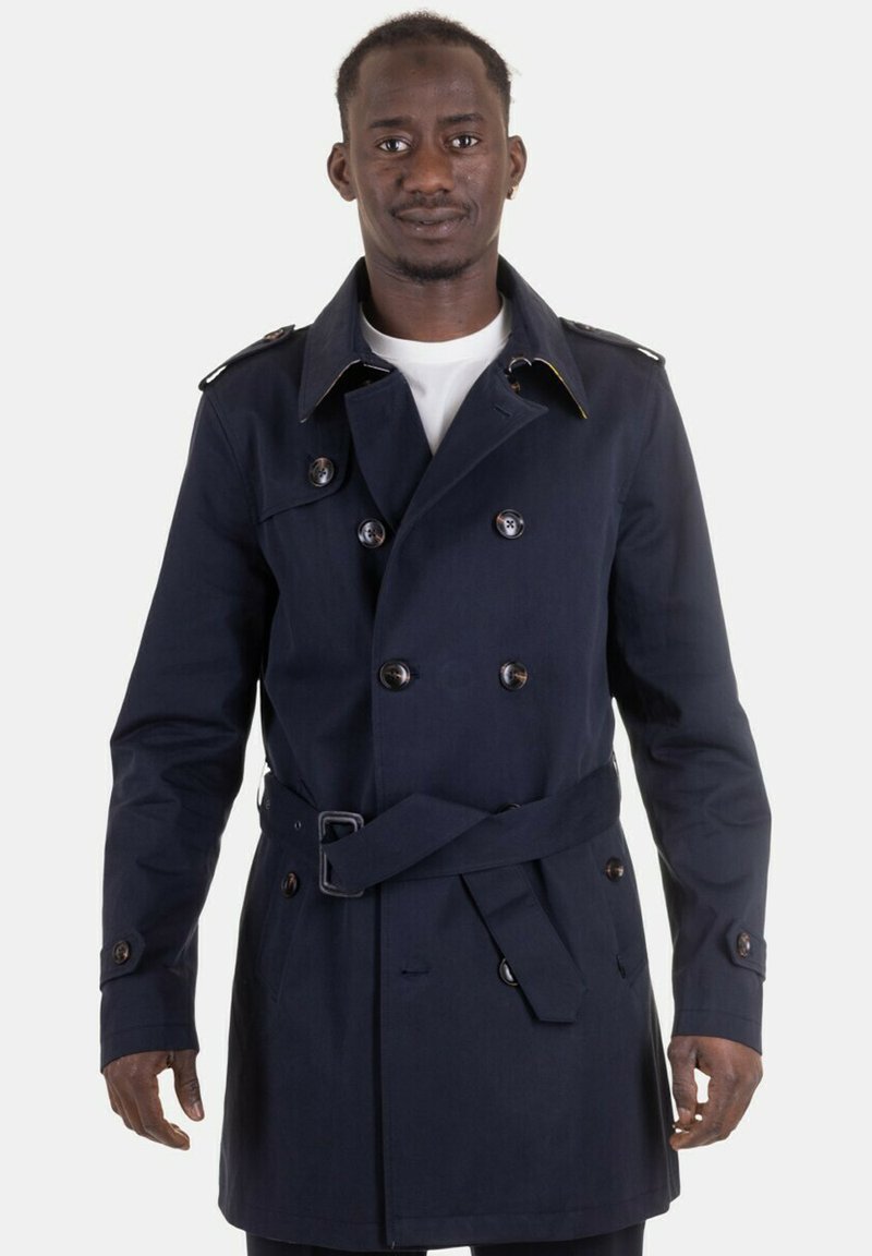 Cappotto trench navy con chiusura doppiopetto, grandi bottoni, spalline e cintura. Realizzato in un tessuto liscio e strutturato.