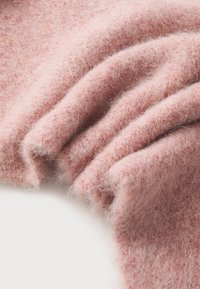 Pehme roosa villane kangas, millel on karvane tekstuur, kergelt volditud ja kihiline välimus. Kergelt heatherdud peene kiuga kogu pinna ulatuses.