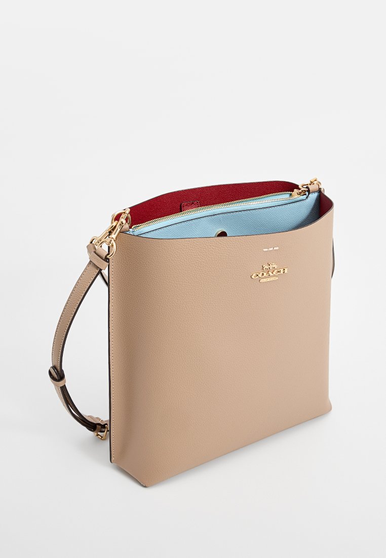 Sac fourre-tout en cuir beige avec quincaillerie dorée, présentant un intérieur rouge et bleu. Inclut une bandoulière détachable et une surface texturée.