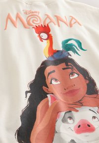 Moana hviler hagen på en smilende gris med en farverig hane siddende på hendes hoved, under Disney Moana-logoen.