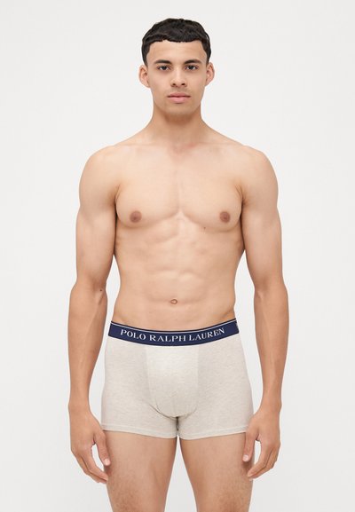 Smėliniai bokseriai su tamsiai mėlynu elastiniu juosmeniu, ant kurio užrašyta "POLO RALPH LAUREN", vientisa medžiaga, prigludusi forma.