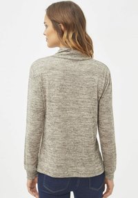 Top de manga larga en punto gris jaspeado. Presenta un cuello vuelto y hombros sin costuras. Corte holgado con dobladillo curvado y puños acanalados.