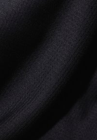 Svart stickad tyg med en slät textur. Materialet har ett subtilt, enhetligt mönster och en lätt glans.