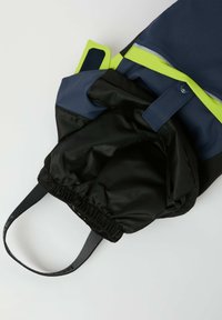 Musta ja laivastonsininen vedenpitävä laukku, jossa on kiristettävä suu, kontrastivärinen neonvihreä yksityiskohta ja kestävä kantohihna kiinnitettynä.
