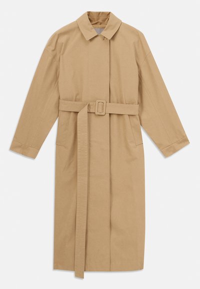 Beige hosszú trench kabát széles gallérral, hosszú ujjakkal, övvel csattal a deréknál és oldalsó zsebekkel, fehér háttérre fektetve.