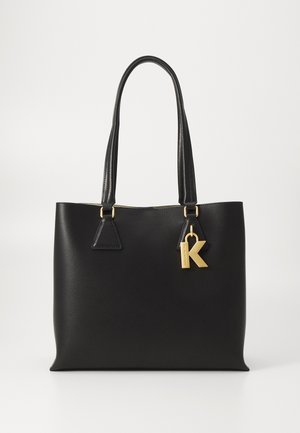 Sac fourre-tout noir en matériau synthétique lisse, doté de doubles poignées supérieures, de quincaillerie dorée et d'un porte-clés décoratif avec la lettre "K".