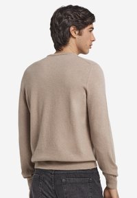 Beige stickad tröja med rund halsringning, långa ärmar och ribbad fåll. Mjuk textur med minimala sömmar och avslappnad passform.