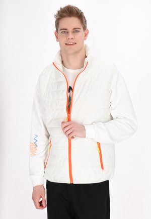 Weißer isolierter Weste mit einem orangefarbenen Reißverschluss und kleinen Taschenakzenten. Die Vorderseite weist ein gestepptes Design und einen hohen Kragen auf. Schwarze Hose getragen.