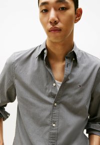 Button-up shirt in black and white gingham pattern, featuring a relaxed fit, short sleeves, and a small logo on the chest.