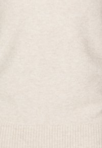 Suéter de malha bege com uma textura suave, bainha canelada e uma aparência lisa e uniforme em todo o tecido.