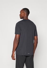 Sort kortærmet trænings T-shirt, let stof, rund halsudskæring, glat tekstur og klassisk pasform, med subtil branding ved kanten.