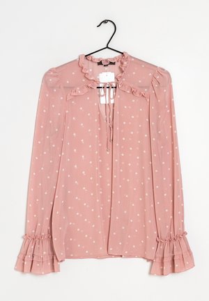 Lichtroze blouse met witte polka dots, gerimpelde kraag en manchetten, keyhole-halslijn met strik, hangend aan een zwarte hanger tegen een witte achtergrond.