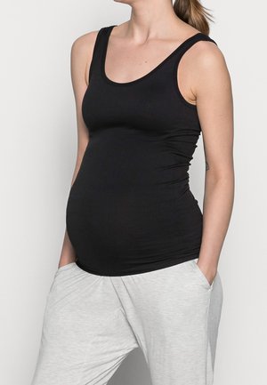 Czarny prążkowany top na ramiączkach z dekoltem w serek, dopasowany fason i regulowane ramiączka, w połączeniu z luźnymi jasnoszarymi spodniami.