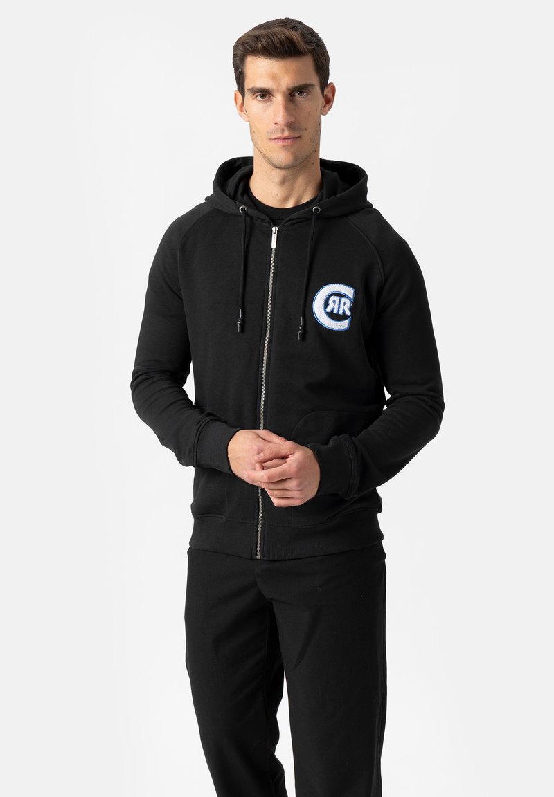 Schwarzer Hoodie mit Reißverschluss und Kordelzugkapuze, gerippten Bündchen und weiß-blauem, rundem Logo auf der Brust. Weicher Stoff, minimalistisches Design.