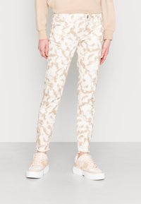 Jeans de color beige claro con un patrón de tie-dye en tonos de crema y marrón, estilo ajustado, cinco bolsillos y sutiles acentos de dobladillo deshilachado.