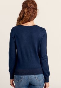 Dunkelblauer Strickpullover mit langen Ärmeln, rundem Ausschnitt und geripptem Saum. Aus weichem Material gefertigt, von hinten präsentiert.