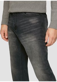 Denim jeans in een vervaagde zwarte kleur, met een slim fit en zichtbare wassing. De stof heeft een gladde textuur, met standaard zakken en naden.
