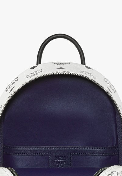 Weißer Leder-Rucksack mit schwarzem Logo-Muster, runder Form, silbernem Reißverschluss und dunkelblauem Innenfutter. Verfügt über einen Obergriff zum Tragen.