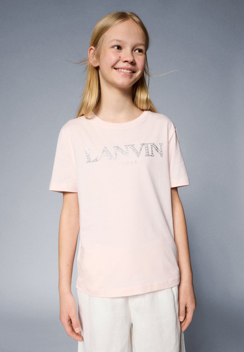 Camiseta de algodón de color rosa claro con mangas cortas, que presenta un logo plateado de "LANVIN PARIS" en el frente. Textura suave y diseño sencillo.