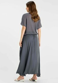 Grijs geribd crop top gecombineerd met een vloeiende grijze maxi-rok. De stof is lichtgewicht met een zachte textuur en een elastische tailleband voor comfort.