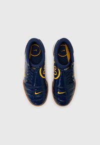 Sapatos de pele sintética azul-marinho com pormenores amarelos, apresentando um bico redondo, atacadores e uma sola de borracha de goma. Inclui um logótipo na língua.