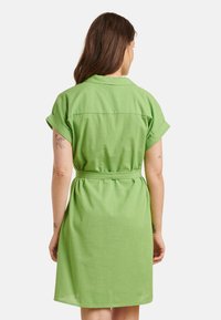 Grünes Kurzarmkleid mit einem Gürtel, aus weichem Stoff gefertigt, hat eine gerade Silhouette und ein Rückenpasse-Detail. Schlichte und legere Gestaltung.