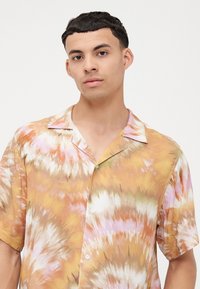 Camisa de manga corta con un vibrante patrón de tie-dye en colores pastel, principalmente naranja y rosa, con un collar clásico y cierre de botones.