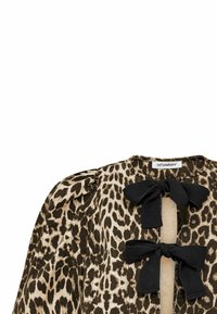 Top con stampa leopardata in beige e marrone, con nastri neri al collo. Presenta maniche a sbuffo e un colletto rotondo.