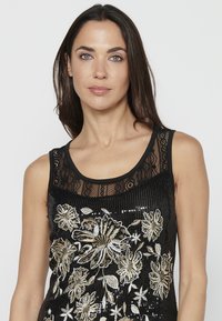 Top negru fără mâneci, cu decolteu din dantelă, având broderie florală complicată în nuanțe de aur și argint și detalii cu paiete pe toată suprafața.