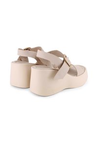 Sandalias de plataforma beige con anchas correas cruzadas, detalle de hebilla, textura suave de ante y suela de goma gruesa para mayor estabilidad.