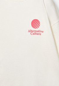 Cream-colored sweatshirt made of cotton, featuring a red circular logo with diagonal stripes and text reading "Alternative Culture."