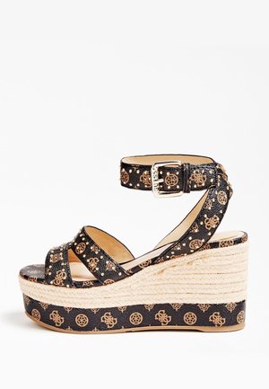 Sandale compensée noire avec motif monogramme marron, bride de cheville avec boucle et semelle plateforme en corde tressée.