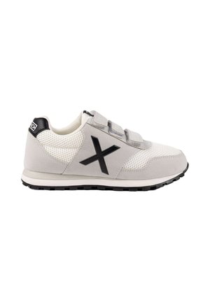 Zapatilla deportiva gris claro con paneles de malla, logotipo negro en forma de X en el lateral, tres tiras de velcro y suela negra.