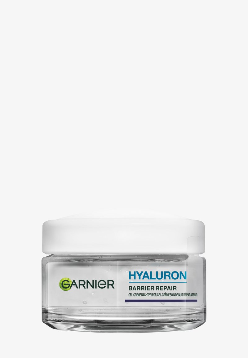 Genomskinlig glasburk med ett vitt lock, med blå och svart text som märker "GARNIER HYALURON BARRIER REPAIR." Gelkrämstrukturen synlig inuti.