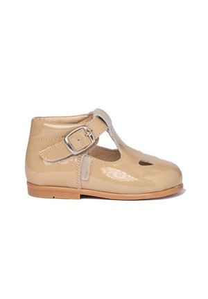 Zapato T-bar de cuero sintético beige con cierre de hebilla, punta redonda, diseño recortado y suela de cuero marrón claro. Textura suave.