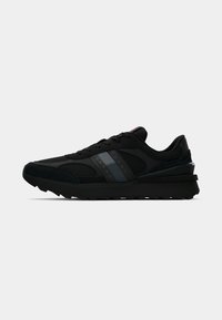 Black athletic shoes with mesh and suede materials, featuring a thick sole, logo accent, and gray stripe detail on the side.